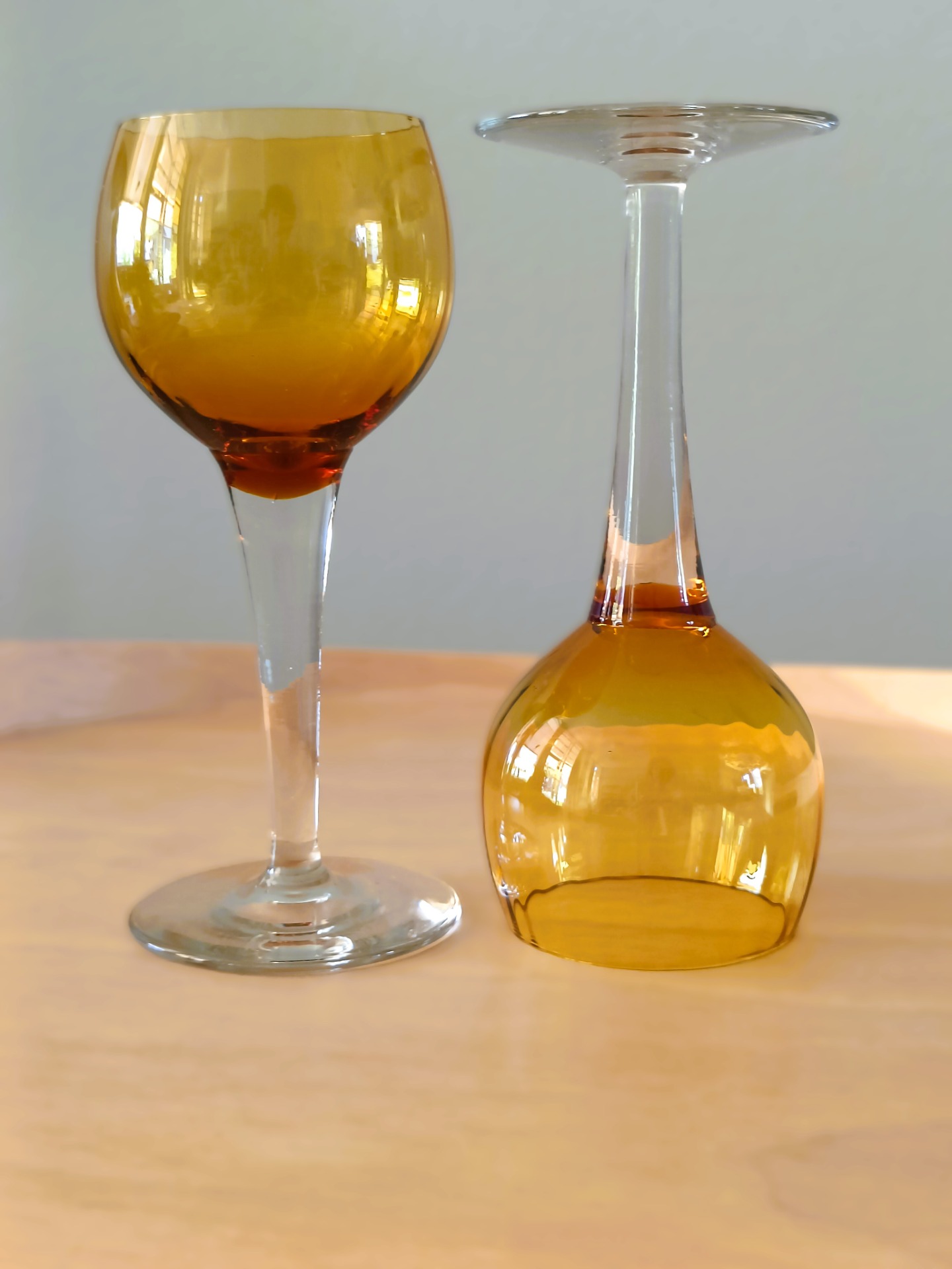 Twee glazen met amberkleurige kelk en een transparante steel en voet.